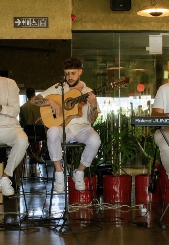 Guitarrista sentado frente a un micrófono, con un teclado a un lado.